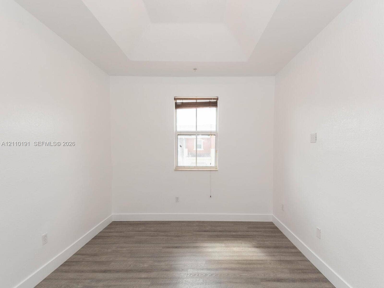 8999 NW 107 Court, #218-1, Miami, Miami, FL 33178 Room featuring tray ceilings, wood-finish flooring, and a central window with integrated blinds