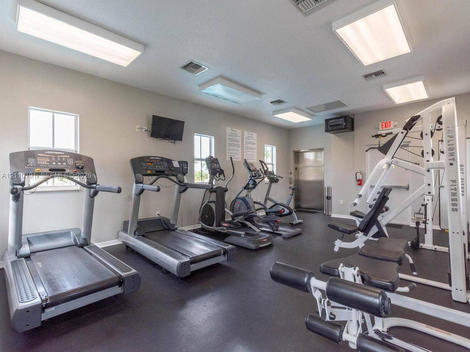 8999 NW 107 Court, #218-1, Miami, Miami, FL 33178 Fitness center featuring rubber flooring, multiple rectangular ceiling-mounted light fixtures, and windows providing natural light