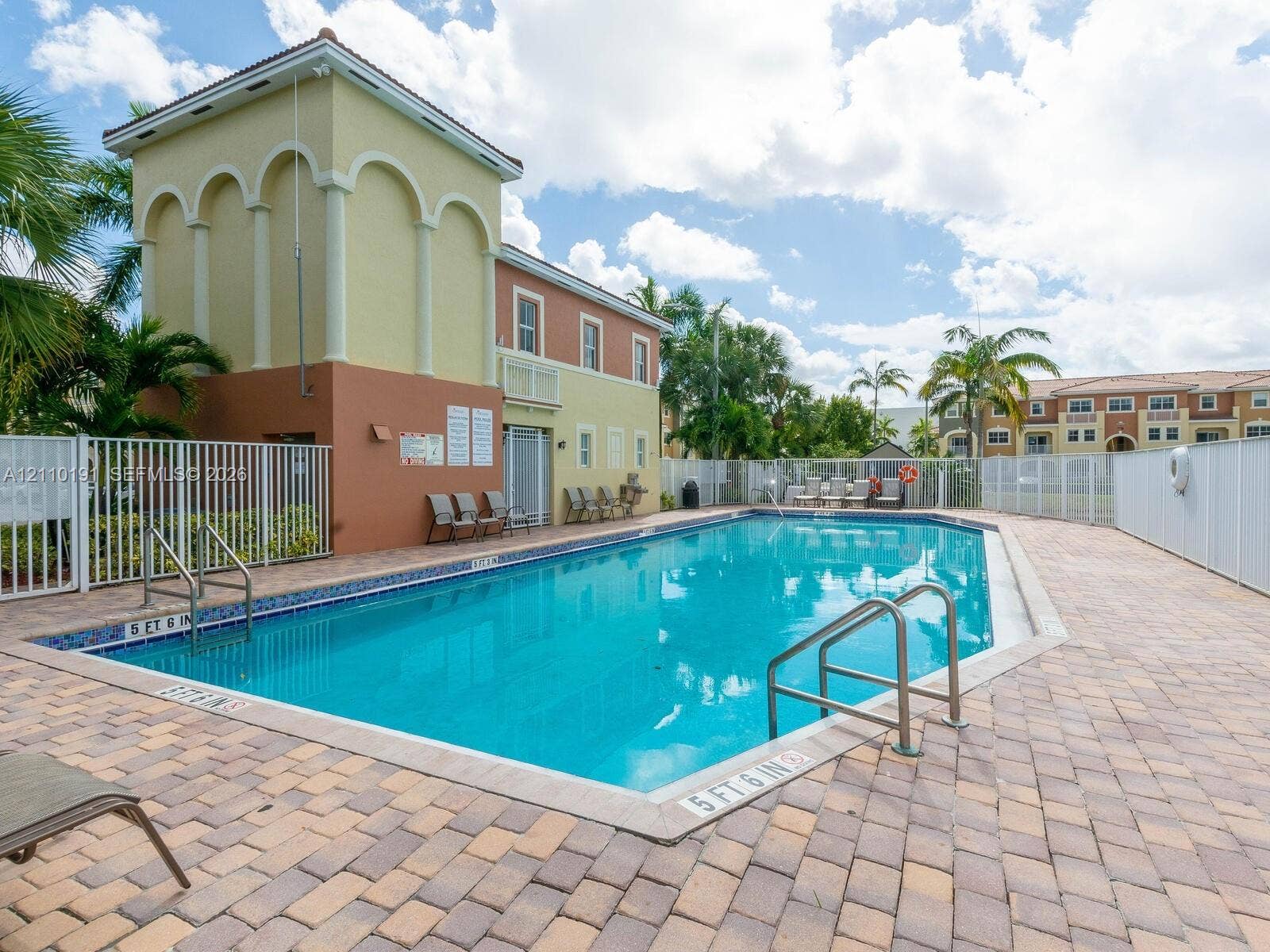 8999 NW 107 Court, #218-1, Miami, Miami, FL 33178 Swimming pool with tiled waterline, concrete paver decking, metal perimeter fencing, and two-story community building