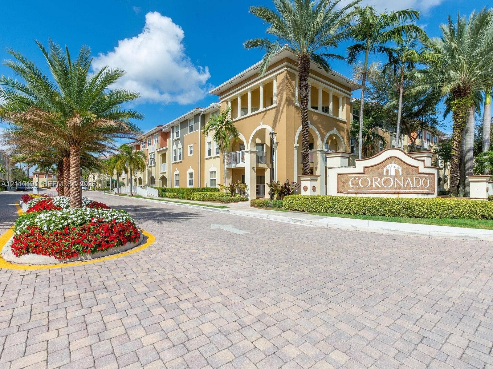 8999 NW 107 Court, #218-1, Miami, Miami, FL 33178 Exterior facade featuring architectural archways, multi-story balconies, paver driveway, mature palm trees, and manicured landscaping