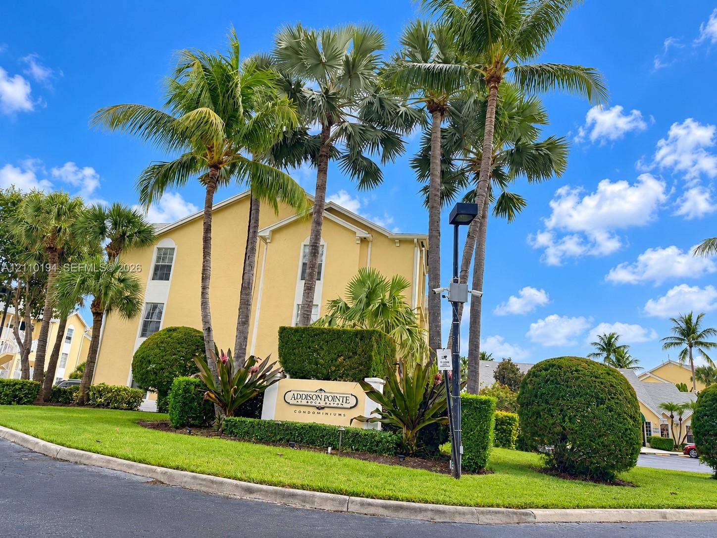 6331 La Costa Drive, #A, Boca Raton, Boca Raton, FL 33433 Multi-story condominium exterior featuring stucco siding, mature palm trees, and professional landscaping with manicured shrubbery