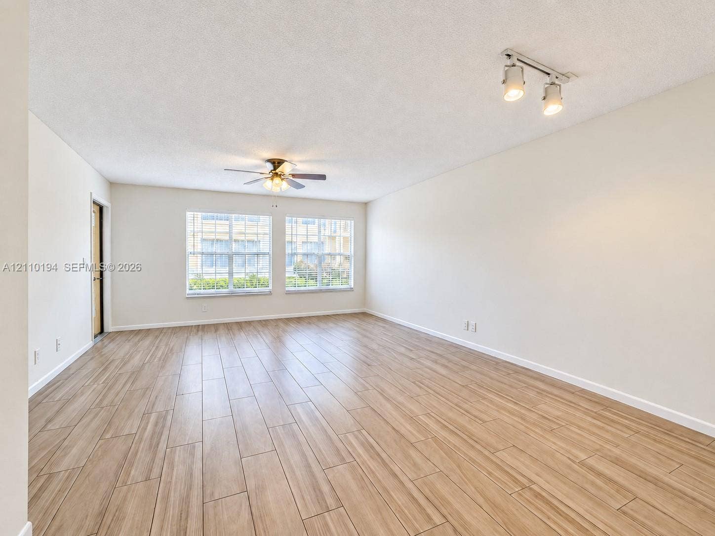 6331 La Costa Drive, #A, Boca Raton, Boca Raton, FL 33433 Neutral-toned interior featuring wood-finish tile flooring, dual-pane windows, a ceiling fan with integrated lighting, and a multi-directional track lighting fixture