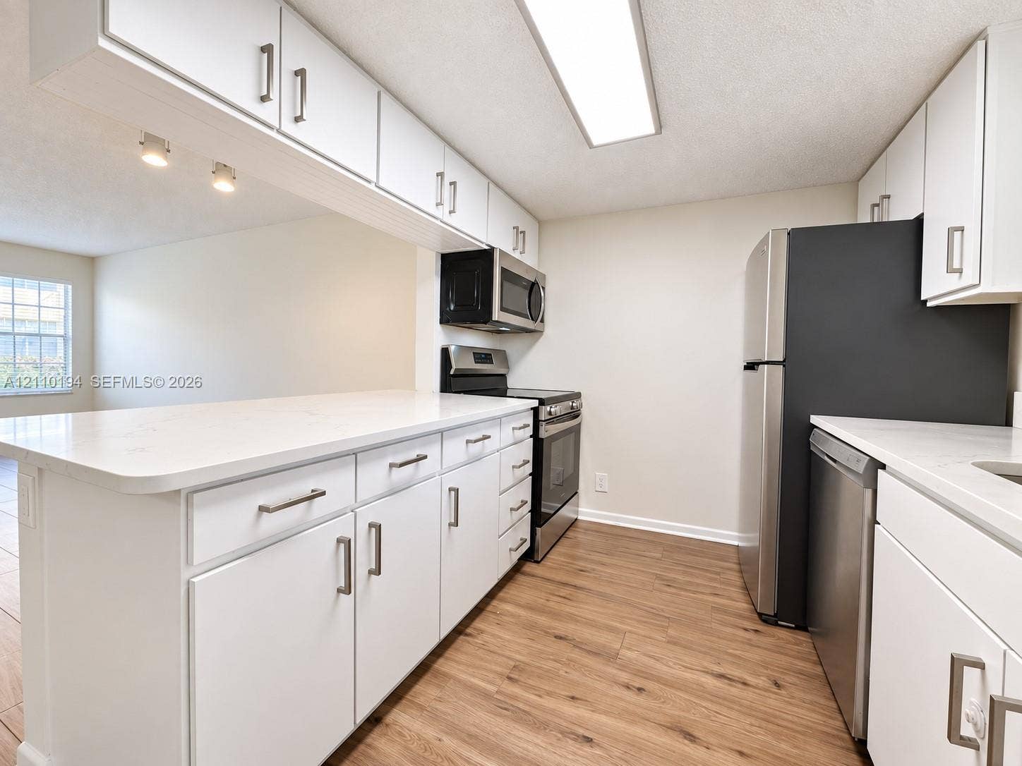 6331 La Costa Drive, #A, Boca Raton, Boca Raton, FL 33433 Kitchen featuring white shaker-style cabinetry, solid-surface countertops, wood-finish flooring, and a stainless steel appliance suite