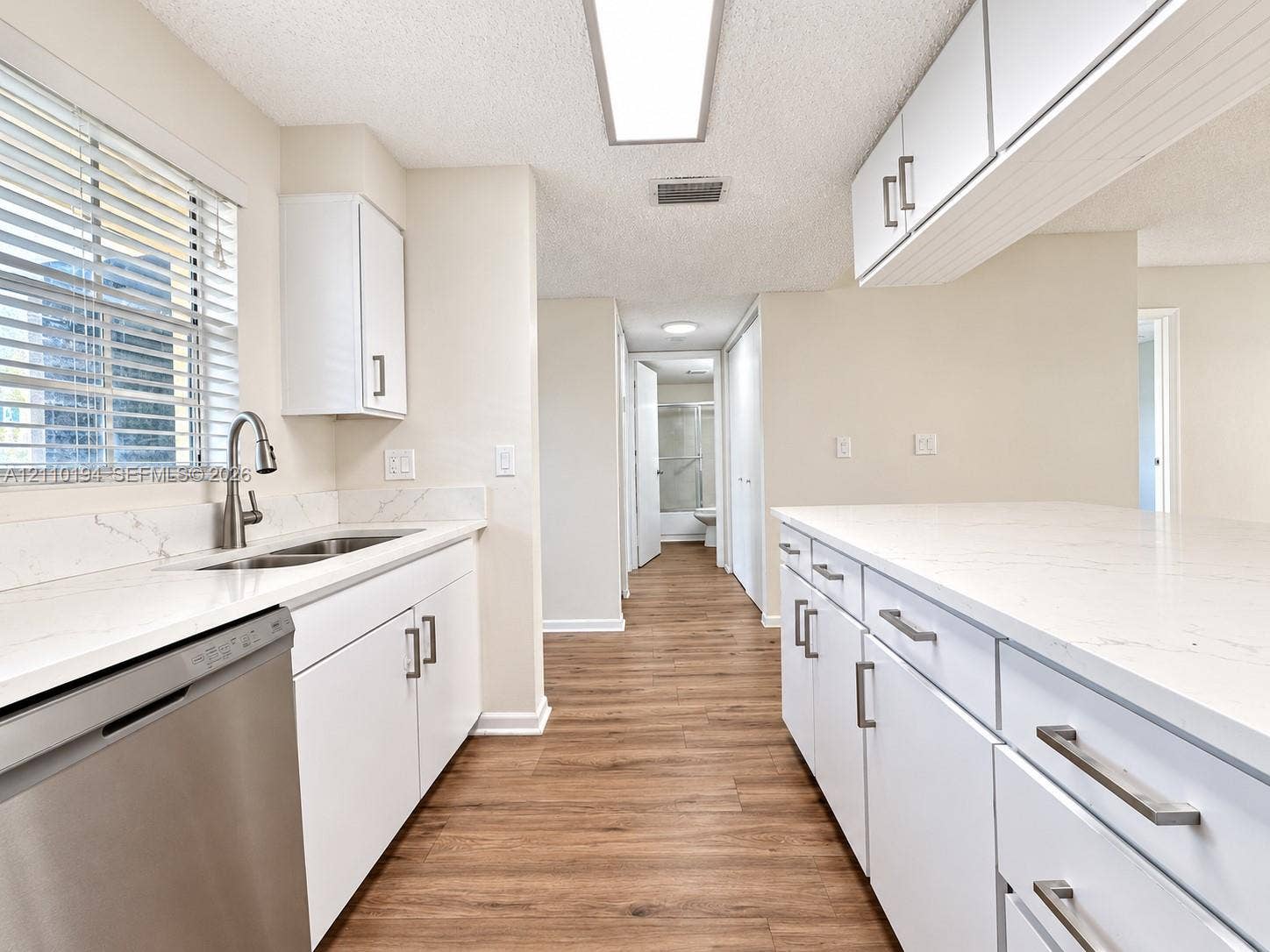6331 La Costa Drive, #A, Boca Raton, Boca Raton, FL 33433 Kitchen featuring white shaker-style cabinetry, quartz countertops with veining, stainless steel undermount sink with gooseneck faucet, stainless steel dishwasher, and wood-finish flooring