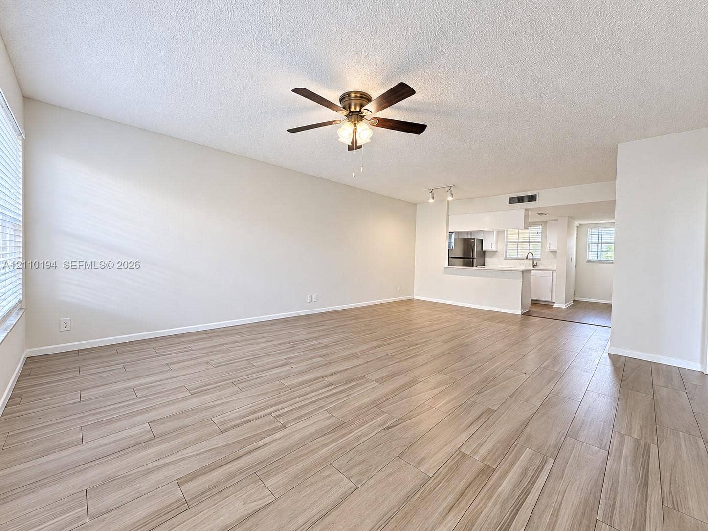 6331 La Costa Drive, #A, Boca Raton, Boca Raton, FL 33433 Open-concept interior featuring wood-finish tile flooring, ceiling fan with integrated lighting, and breakfast bar