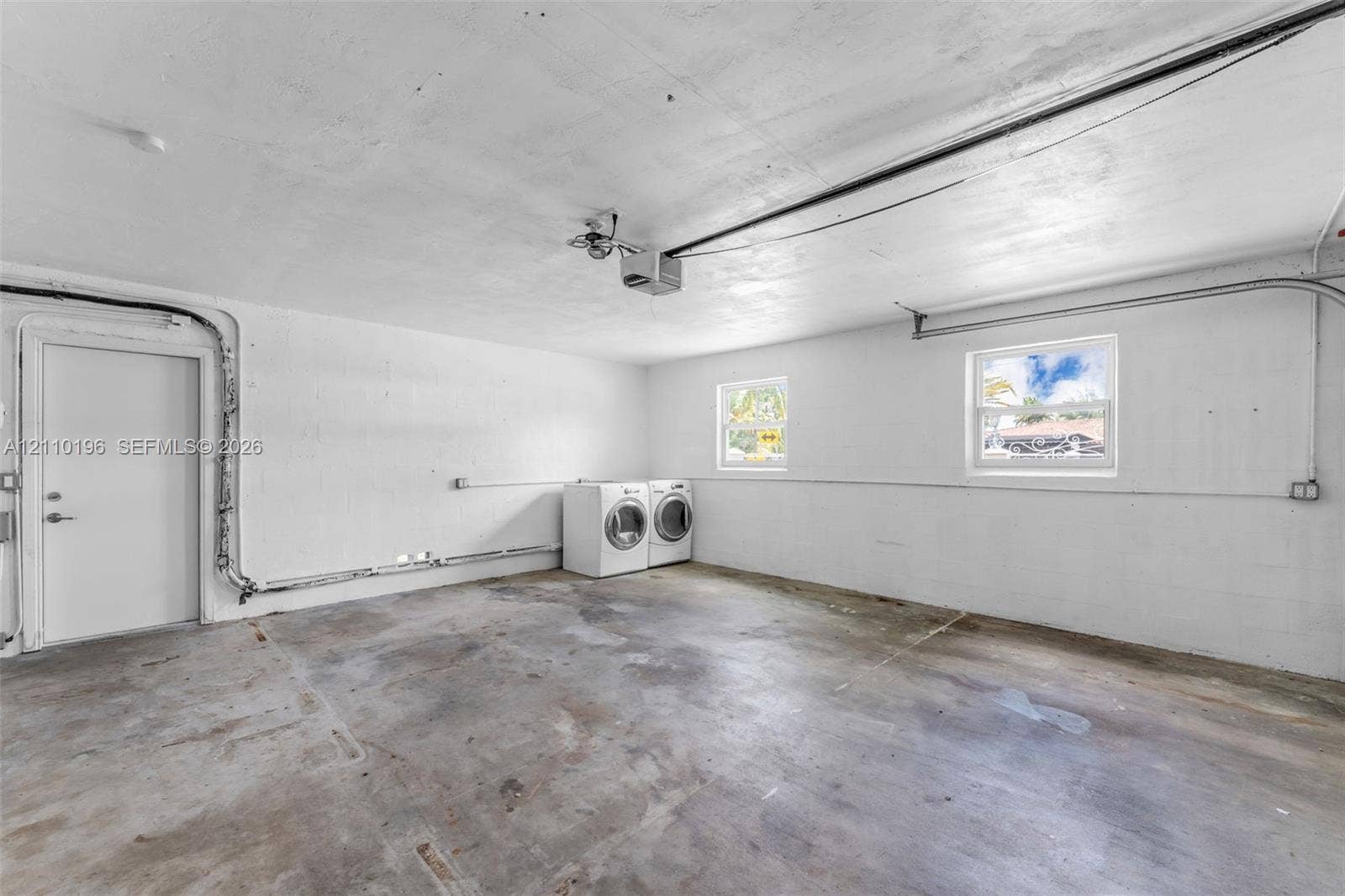 4400 SW 89th Avenue, #4400, Miami, Miami, FL 33165 Garage space featuring concrete flooring, painted block walls, two windows, and an exterior access door