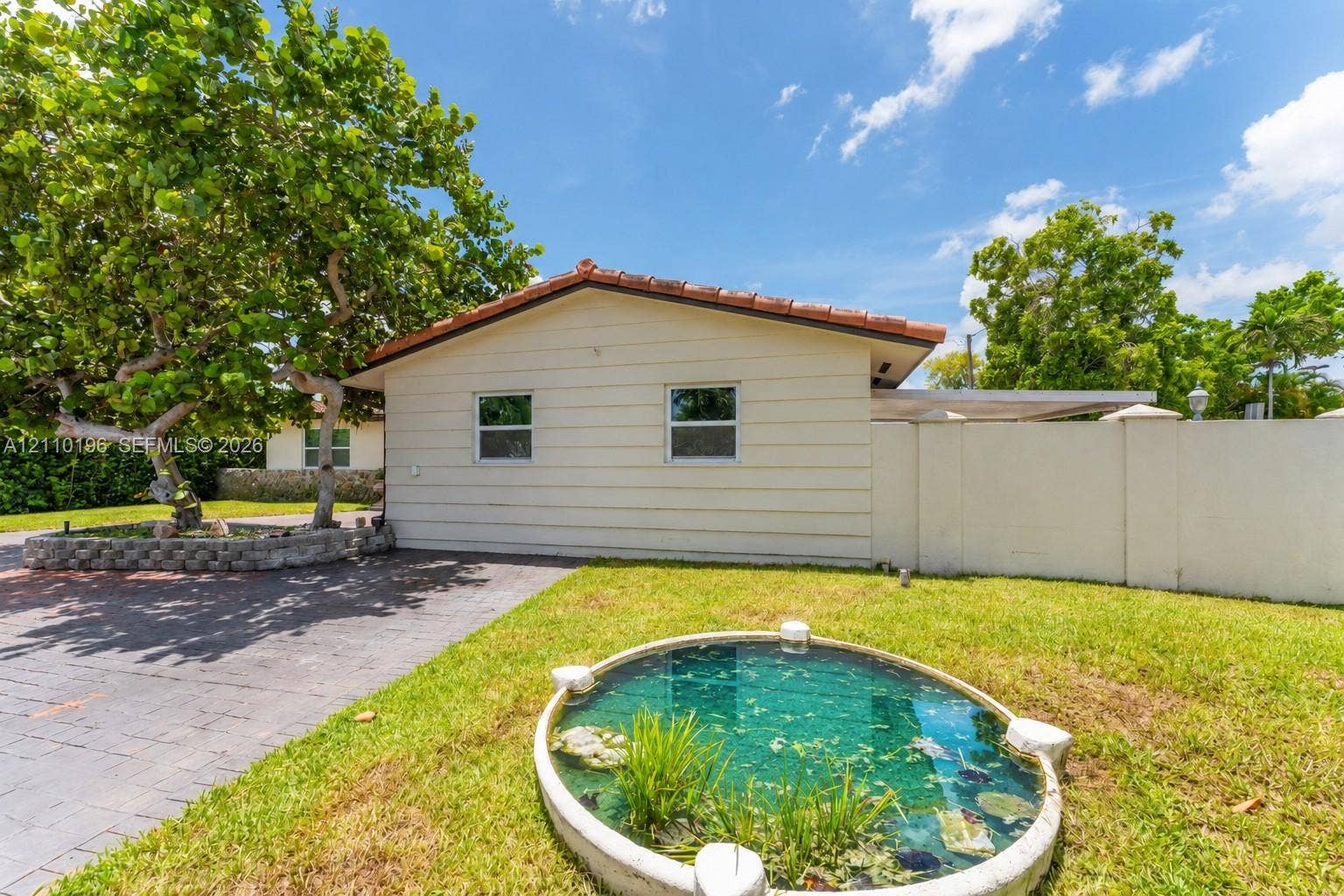 4400 SW 89th Avenue, #4400, Miami, Miami, FL 33165 Exterior featuring horizontal siding, a tile roof, paved driveway, stone-bordered planter, and circular water feature