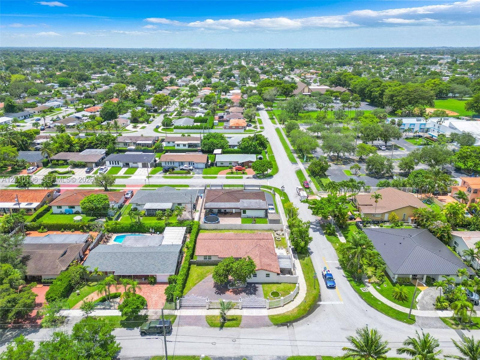 4400 SW 89th Avenue, #4400, Miami, Miami, FL 33165 Aerial perspective of a corner lot property featuring a paved driveway, enclosed perimeter wall, mature landscaping, and a multi-section shingle roof