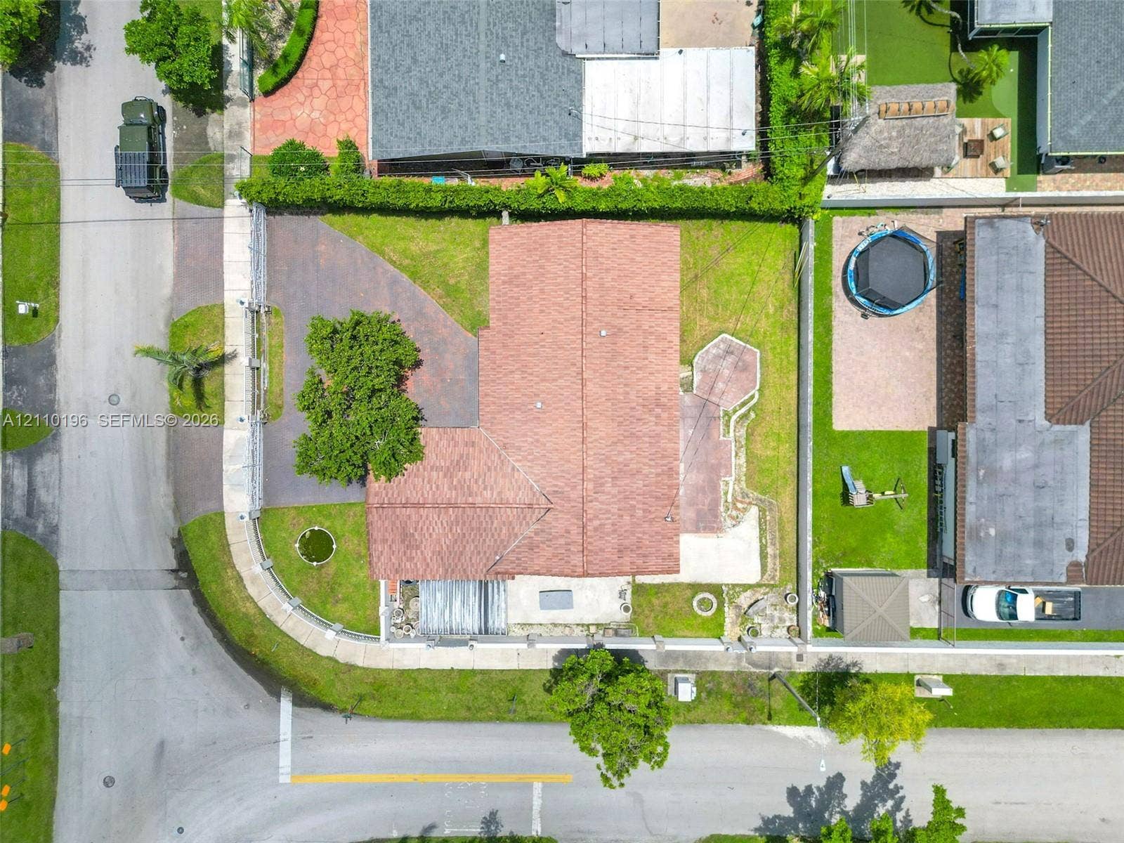 4400 SW 89th Avenue, #4400, Miami, Miami, FL 33165 Aerial perspective of a corner lot property featuring a shingle roof, expansive green space, paved driveway, and perimeter fencing