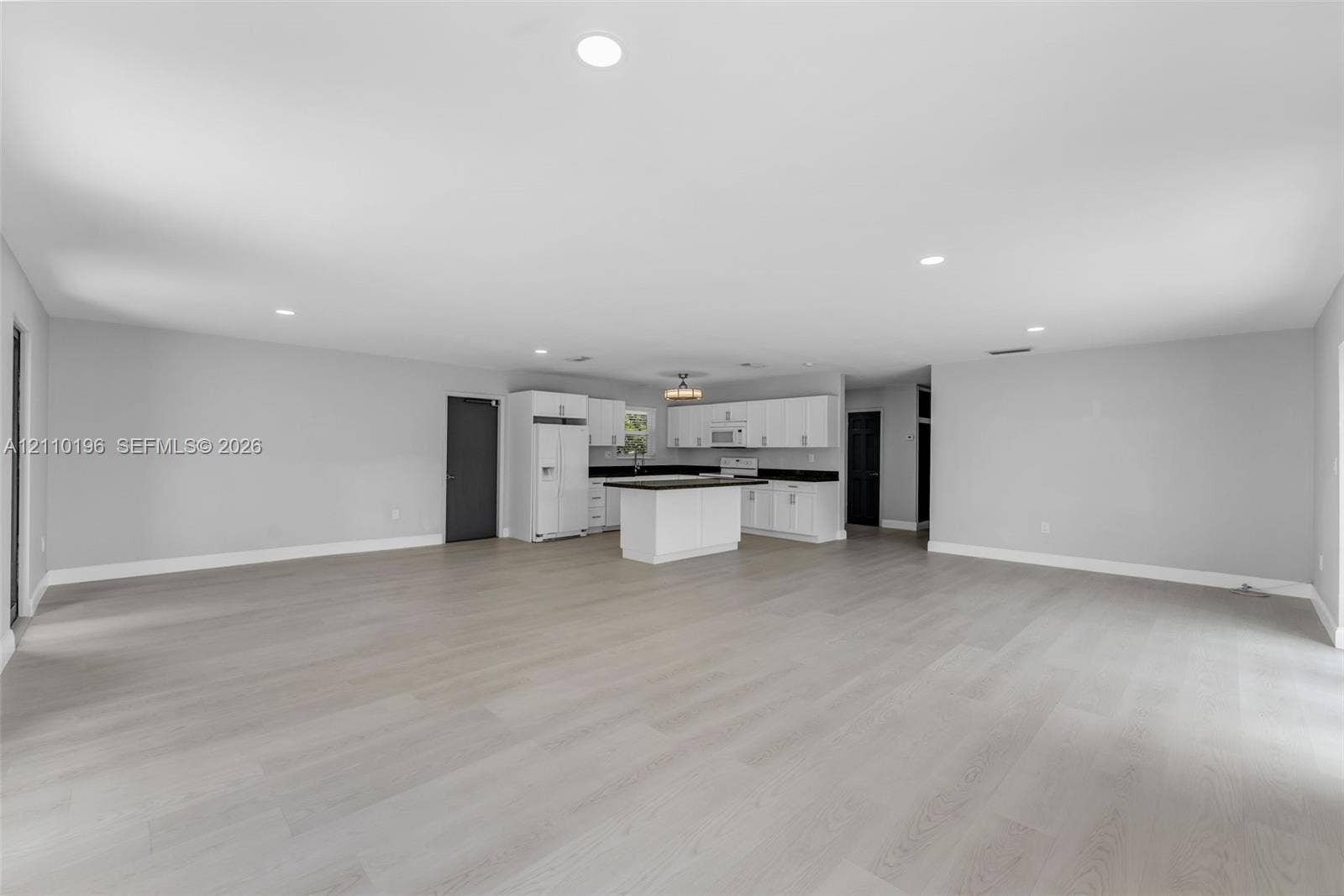 4400 SW 89th Avenue, #4400, Miami, Miami, FL 33165 Open-concept interior featuring light wood-finish flooring, recessed lighting, and a kitchen equipped with white cabinetry, a center island, and dark-toned countertops