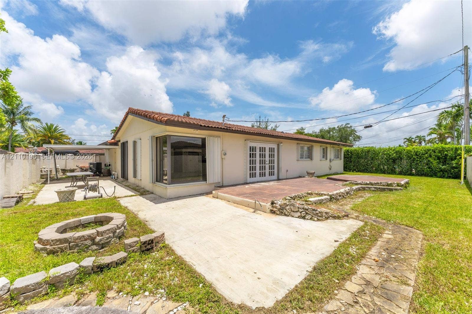 4400 SW 89th Avenue, #4400, Miami, Miami, FL 33165 Exterior backyard featuring a concrete patio, stone-bordered fire pit, multi-level terrace, and covered side patio area