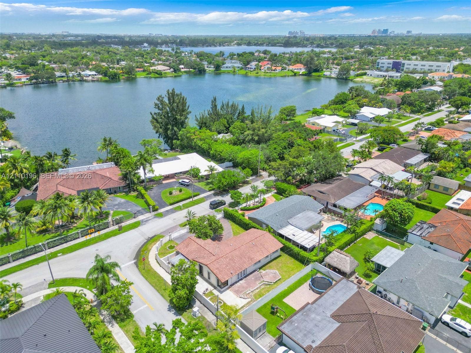 4400 SW 89th Avenue, #4400, Miami, Miami, FL 33165 Aerial perspective of a lakefront residential lot featuring a tile roof, paved driveway, masonry wall perimeter, and mature landscaping