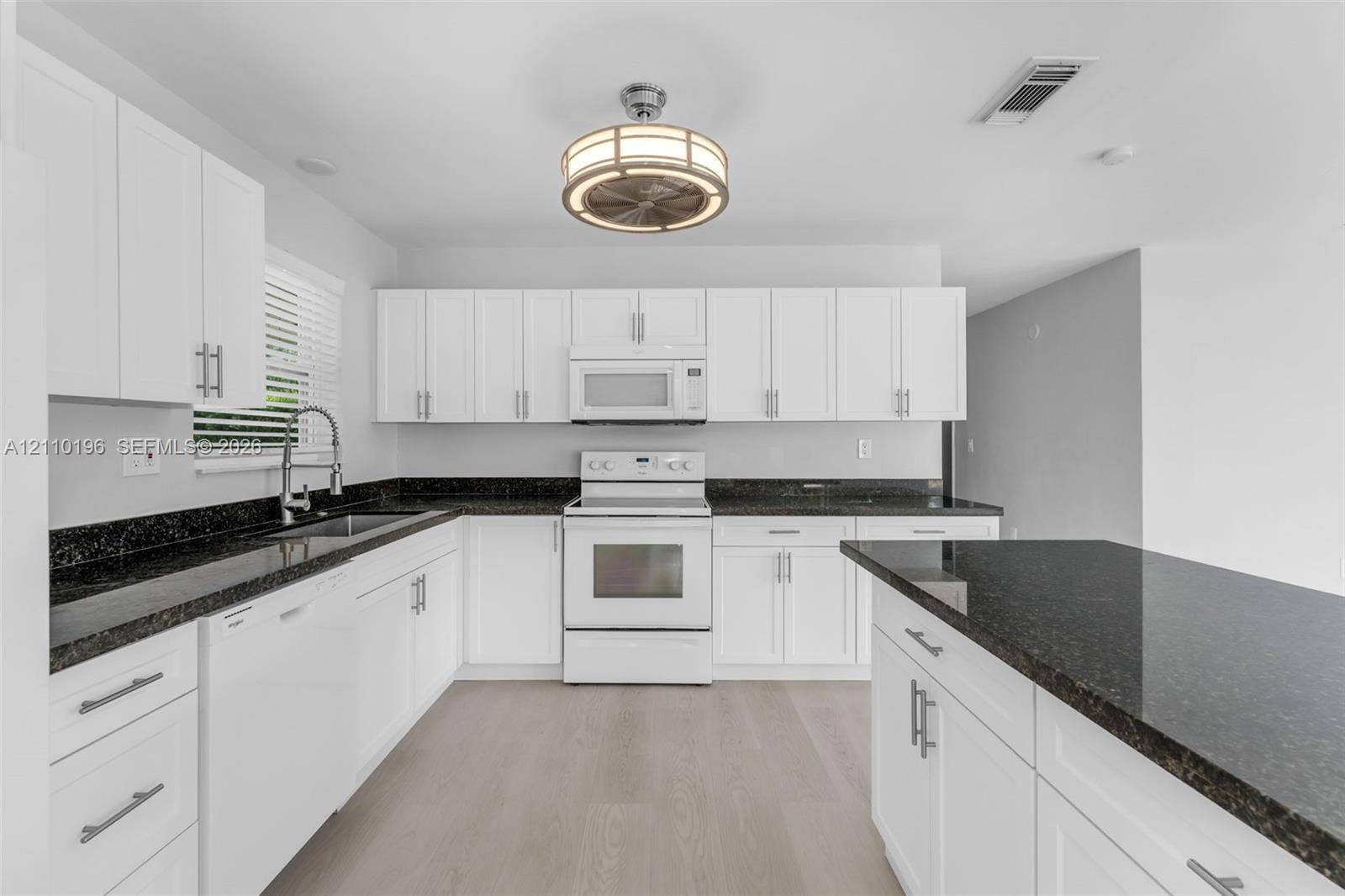 4400 SW 89th Avenue, #4400, Miami, Miami, FL 33165 Kitchen featuring white shaker-style cabinetry, dark stone countertops, an integrated island, wood-finish flooring, and a circular drum-style light fixture