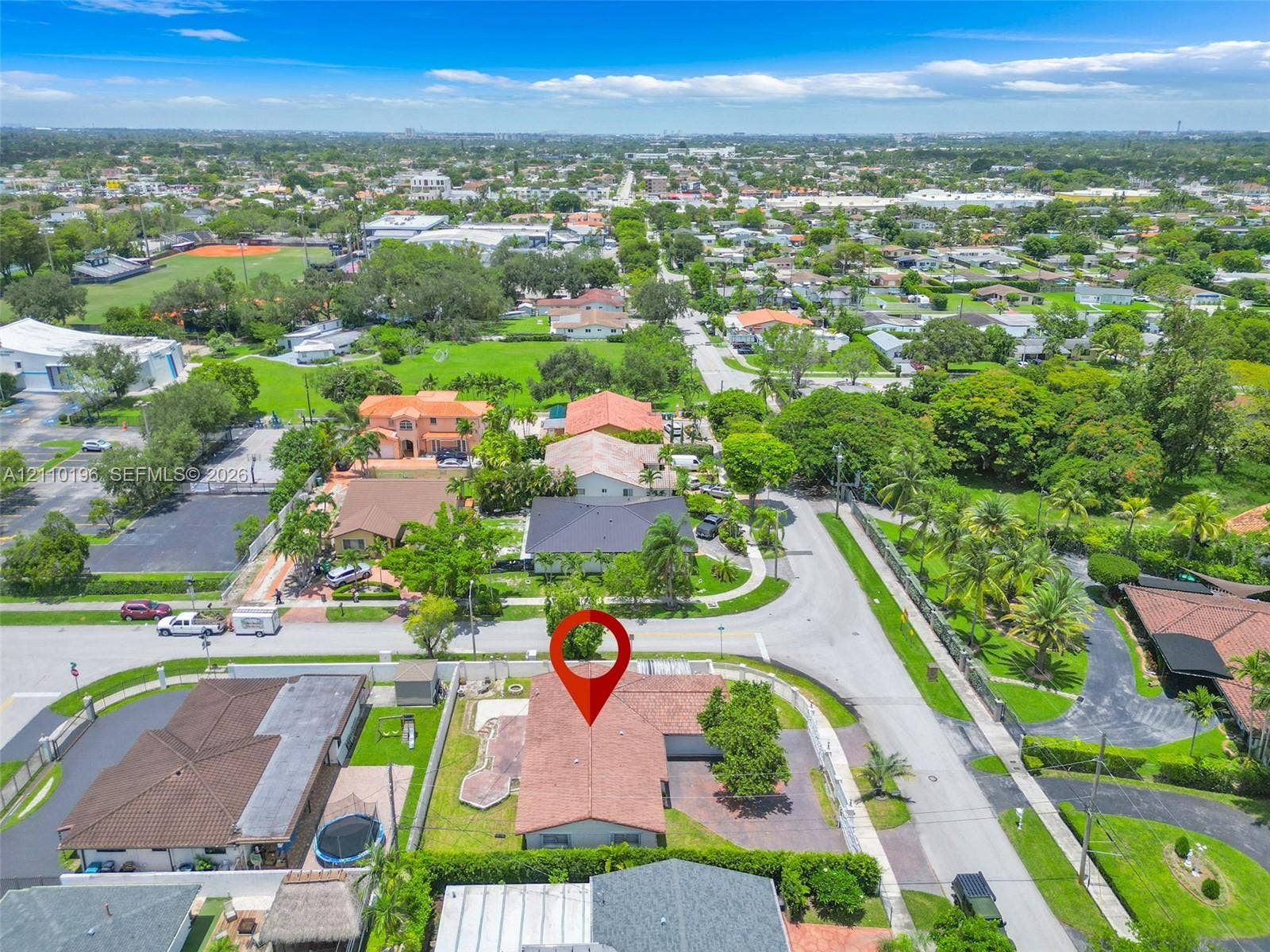 4400 SW 89th Avenue, #4400, Miami, Miami, FL 33165 Aerial perspective of a corner lot property featuring a low-slope roof, hardscaped driveway, perimeter block wall, and mature landscaping