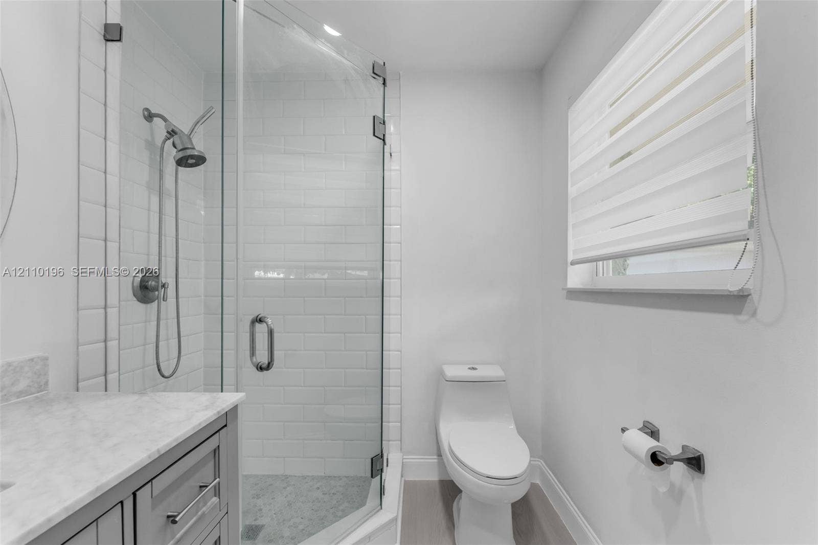 4400 SW 89th Avenue, #4400, Miami, Miami, FL 33165 Walk-in shower featuring white subway tile surround, glass enclosure, and hand-held shower fixture, paired with a stone-top vanity and one-piece toilet