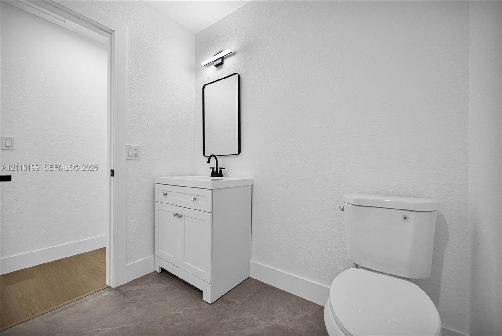 10741 SW 165th Street, Miami, FL 33157 White vanity with storage cabinet, rectangular sink, matte black faucet, rectangular mirror, and matte black wall-mounted vanity light fixture