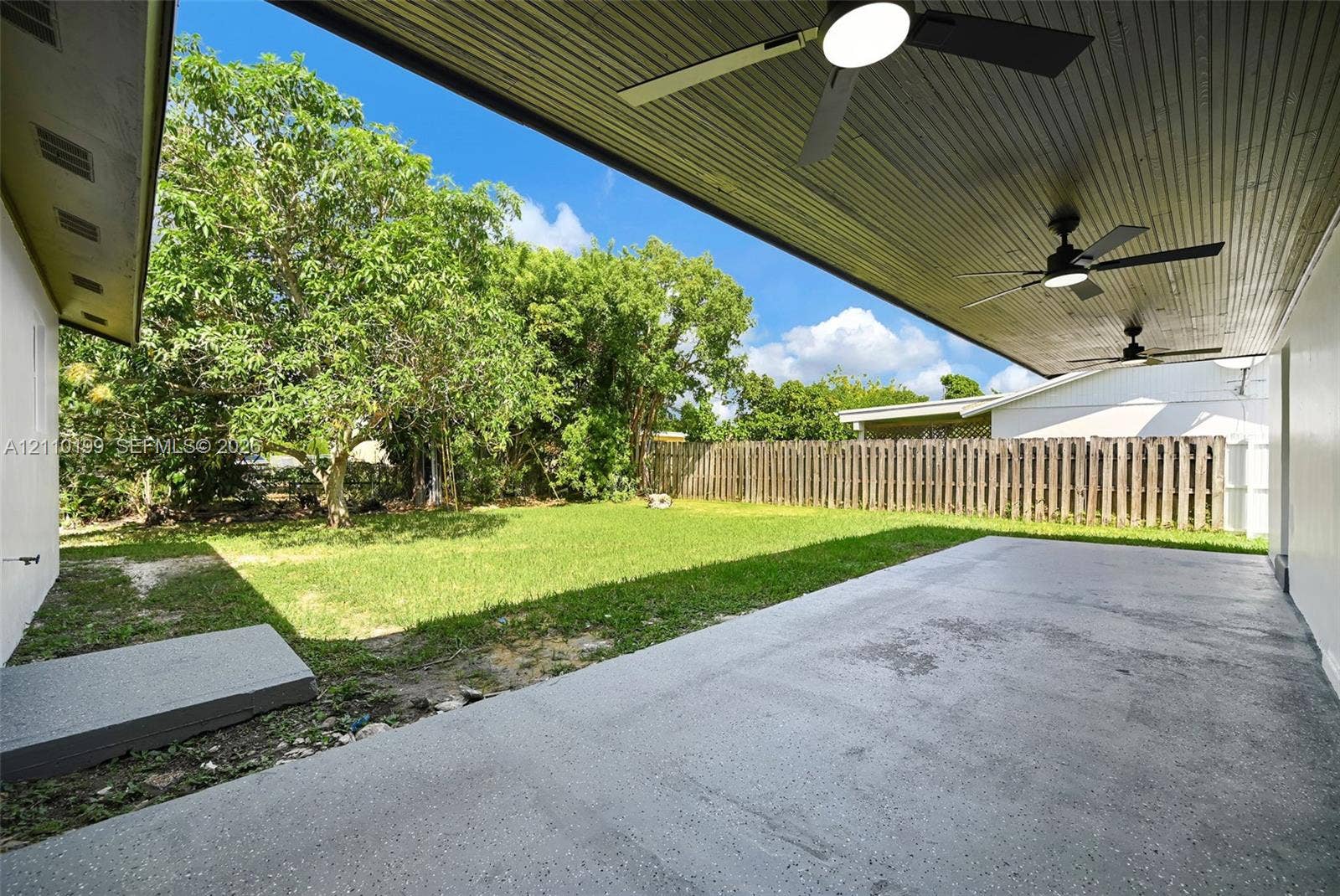 10741 SW 165th Street, Miami, FL 33157 Covered patio featuring recessed ceiling fans, concrete flooring, and a fenced backyard with mature trees