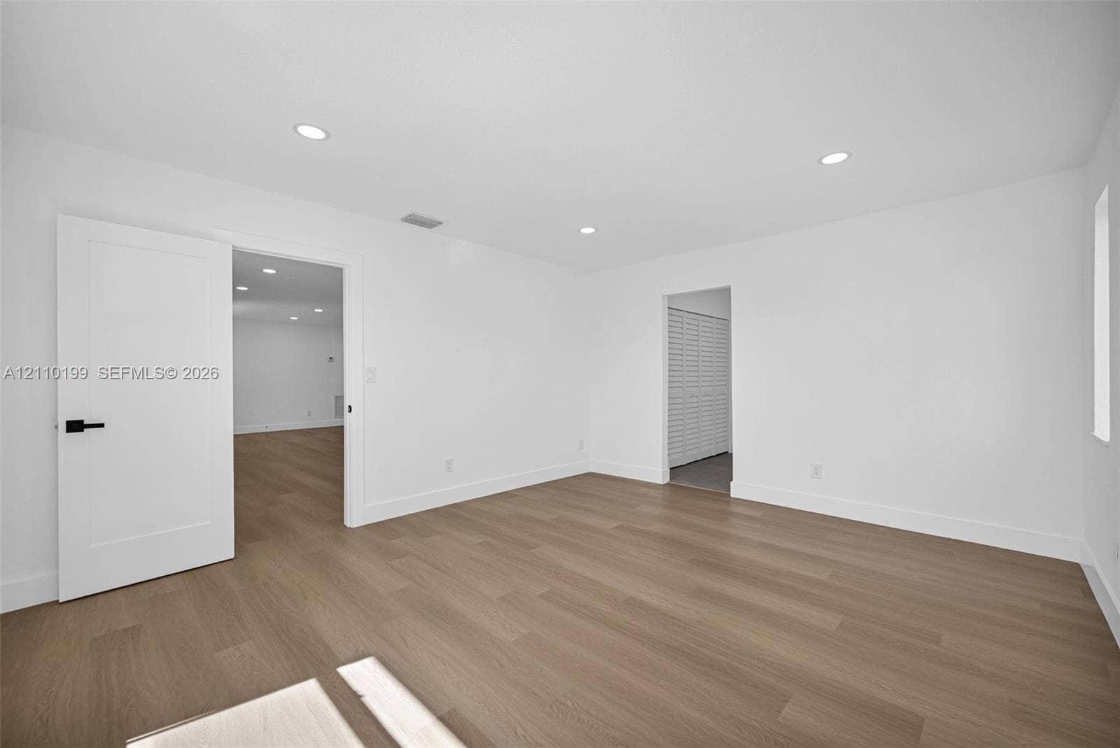 10741 SW 165th Street, Miami, FL 33157 Interior space featuring wood-finish flooring, recessed lighting, and a white interior door with matte black hardware