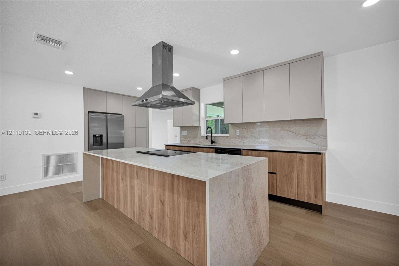 10741 SW 165th Street, Miami, FL 33157 Kitchen featuring flat-panel two-tone cabinetry, central island with waterfall countertop, stainless steel chimney-style range hood, stone-finish backsplash, and wood-finish flooring