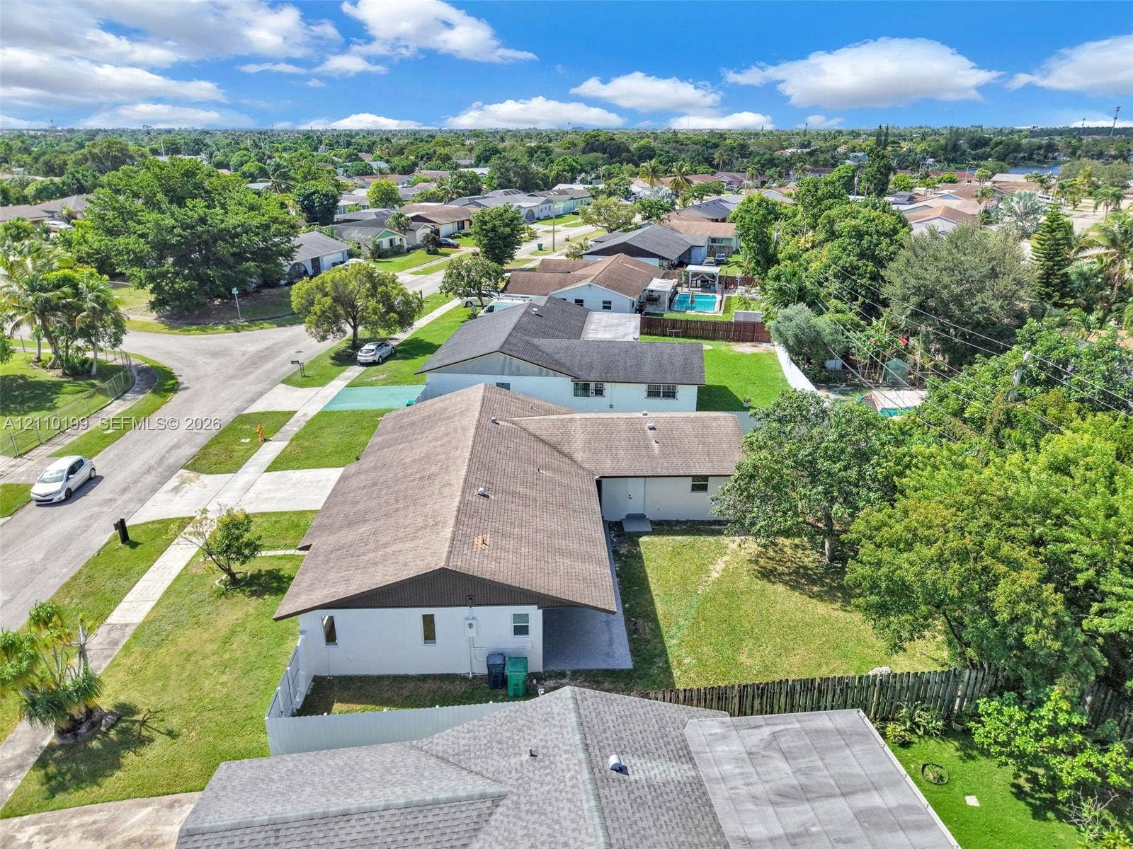 10741 SW 165th Street, Miami, FL 33157 Aerial view featuring a multi-pitched shingle roof, white exterior siding, concrete driveway, and a fenced backyard with mature trees