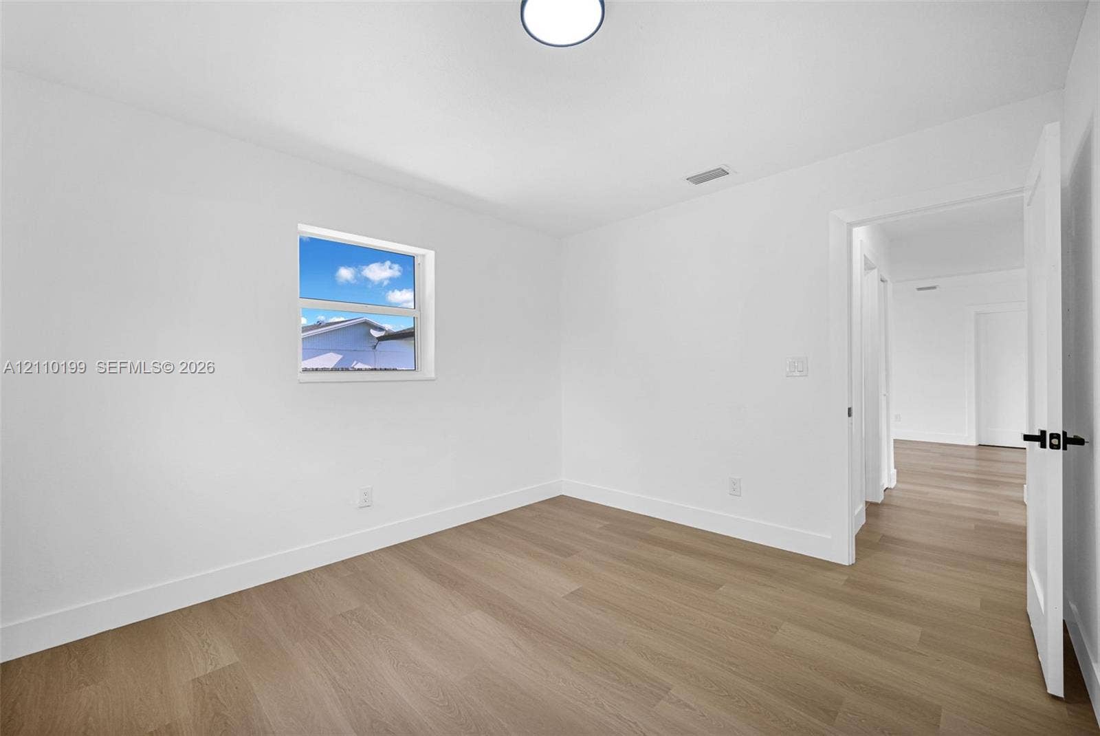 10741 SW 165th Street, Miami, FL 33157 Neutral interior room featuring white-painted walls, wood-finish flooring, a single-hung window, and a recessed ceiling light fixture