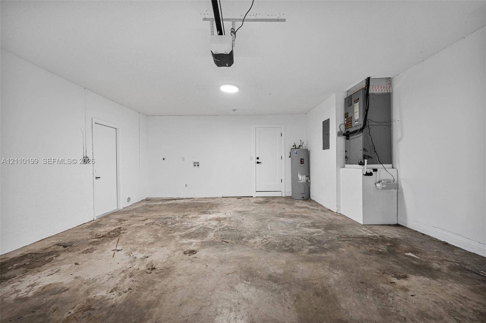 10741 SW 165th Street, Miami, FL 33157 Garage interior featuring concrete flooring, installed HVAC air handler, built-in water heater, and automatic garage door opener