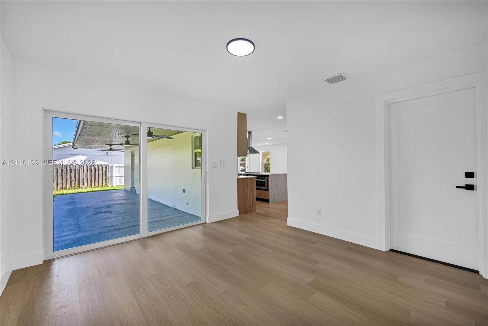 10741 SW 165th Street, Miami, FL 33157 Interior featuring wood-finish flooring, sliding glass doors, and a solid-panel door with matte black hardware