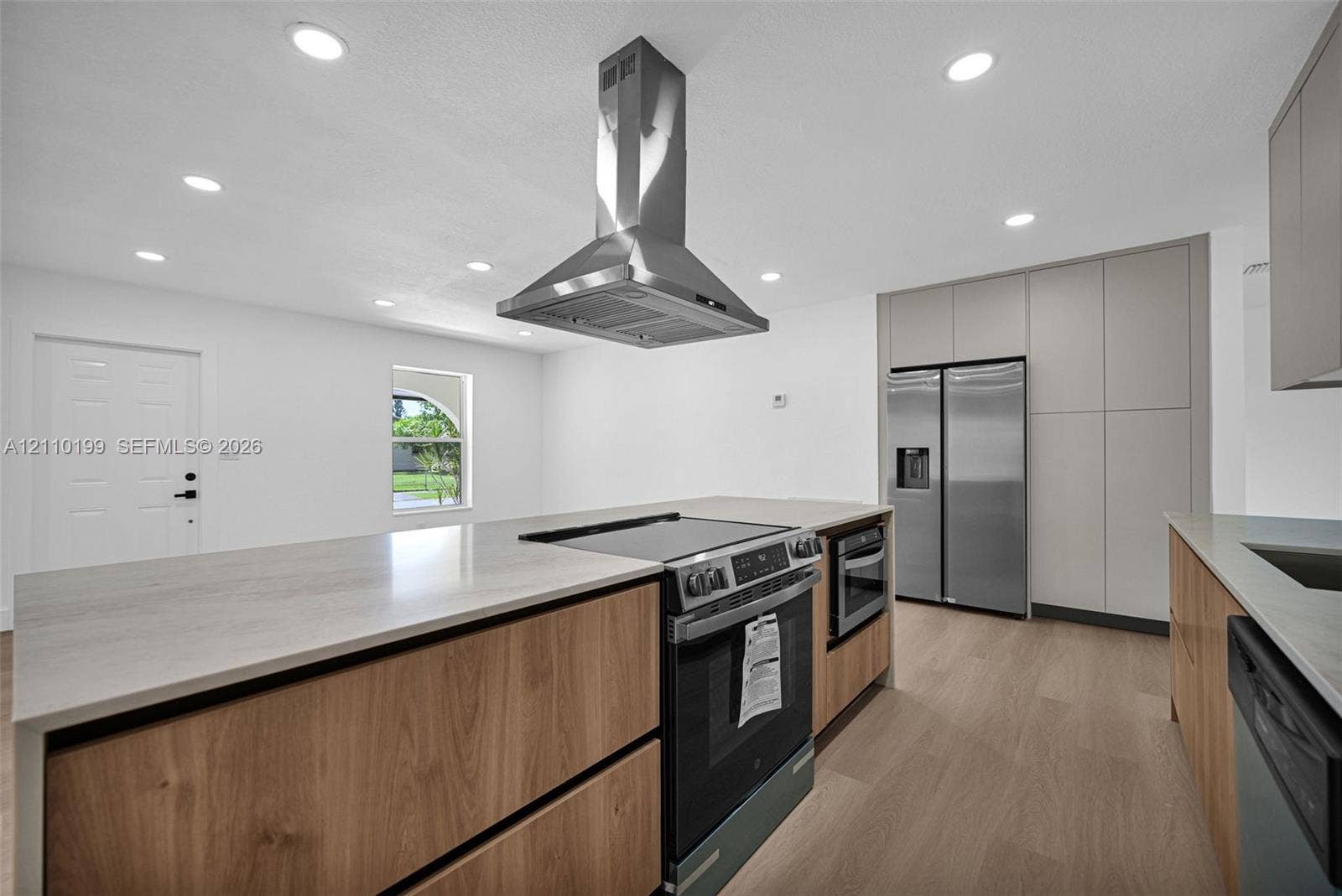 10741 SW 165th Street, Miami, FL 33157 Kitchen featuring wood-finish cabinetry, a central island with a stone-composite countertop, a stainless steel range hood, built-in stainless steel appliances, and recessed lighting