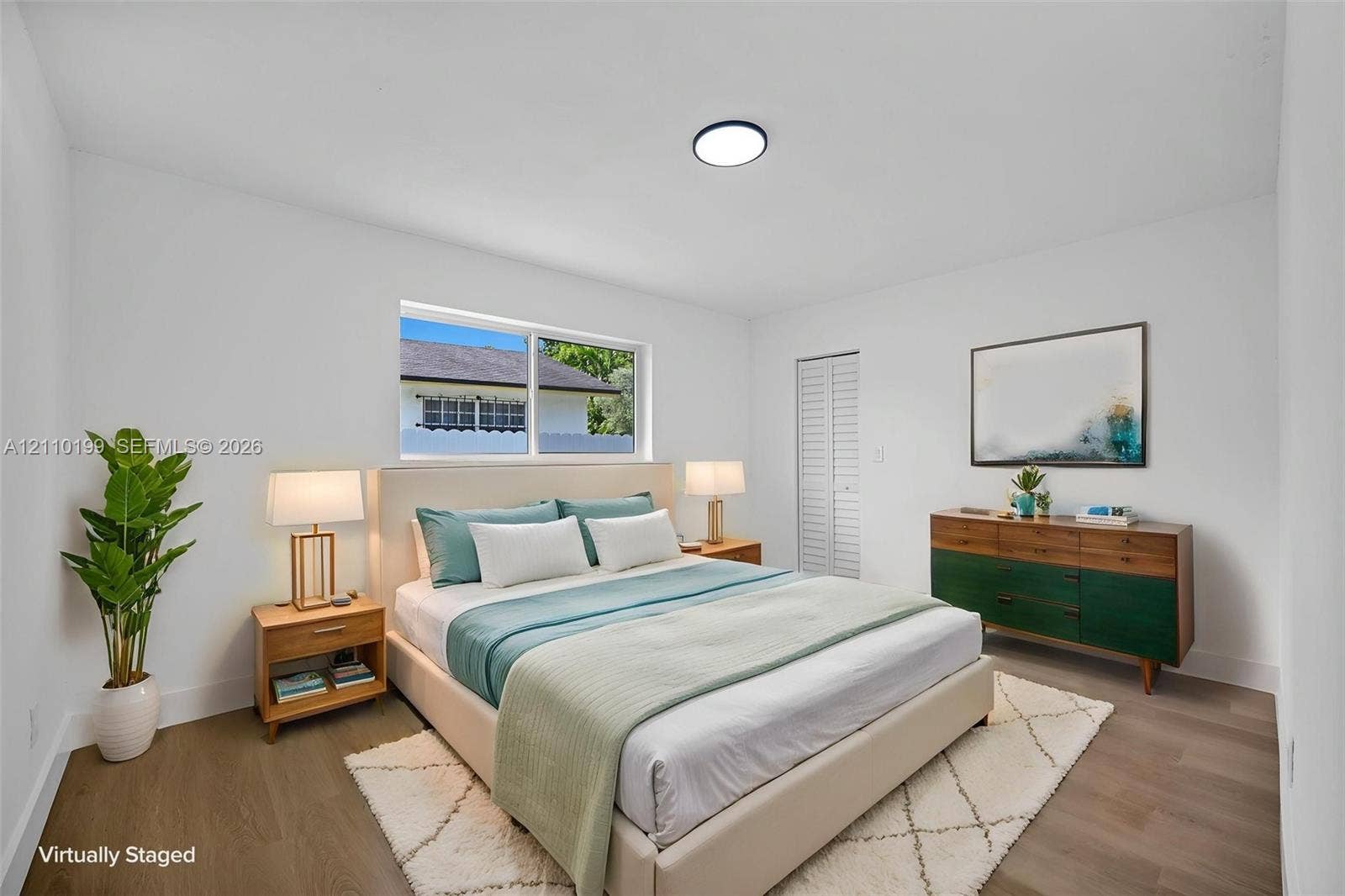 10741 SW 165th Street, Miami, FL 33157 Room featuring wood-finish flooring, a horizontal sliding window, and a closet with bifold louvered doors, illuminated by a flush-mount ceiling fixture