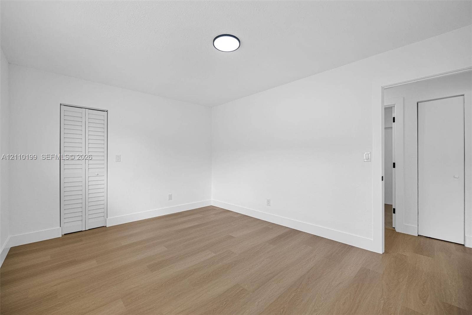 10741 SW 165th Street, Miami, FL 33157 Neutral wall finishes, wood-finish flooring, white louvered bifold closet doors, and flush-mount ceiling lighting