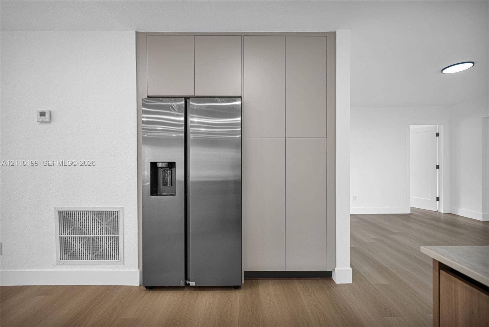 10741 SW 165th Street, Miami, FL 33157 Floor-to-ceiling cabinetry with a matte neutral finish, integrated stainless steel side-by-side refrigerator, and wood-finish flooring