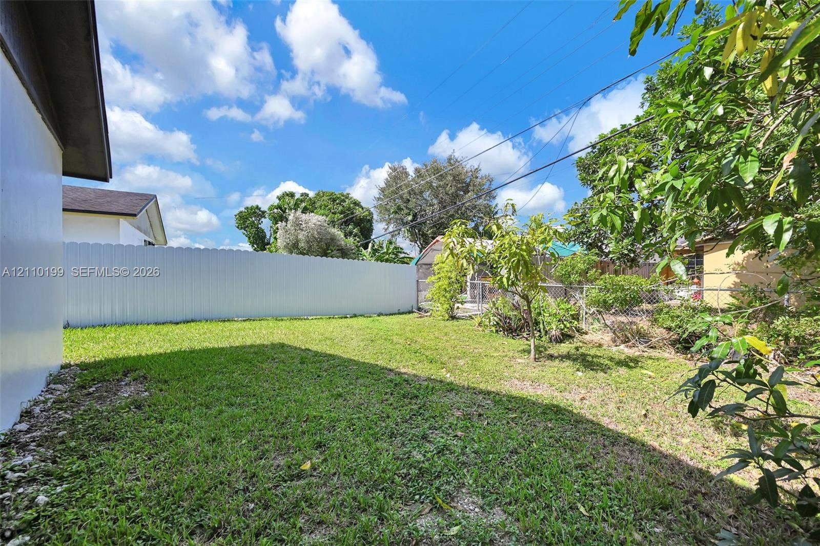 10741 SW 165th Street, Miami, FL 33157 Rear yard featuring a grass lawn, solid vinyl fencing, and mature trees
