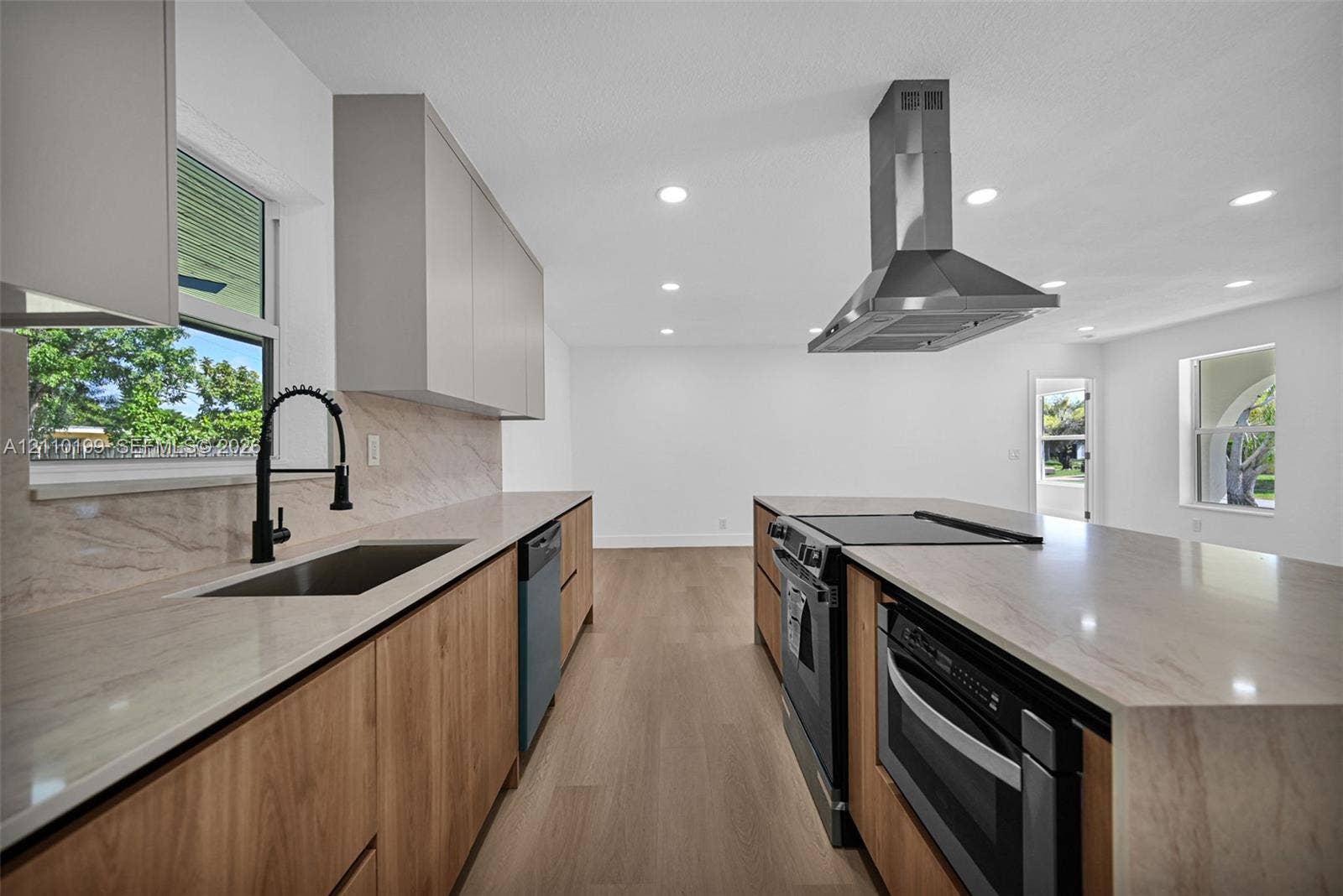 10741 SW 165th Street, Miami, FL 33157 Kitchen featuring wood-finish lower cabinetry, stone-style countertops, matte black faucet, stainless steel range hood, and wood-finish flooring