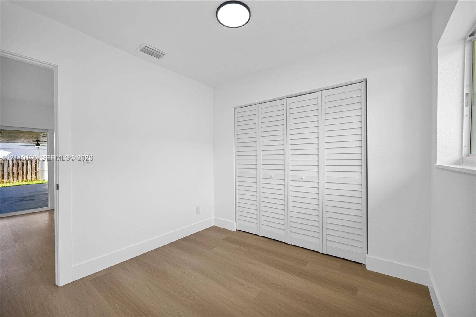 10741 SW 165th Street, Miami, FL 33157 Neutral interior featuring wood-finish flooring, white louvered closet doors, and a ceiling-mounted LED light fixture