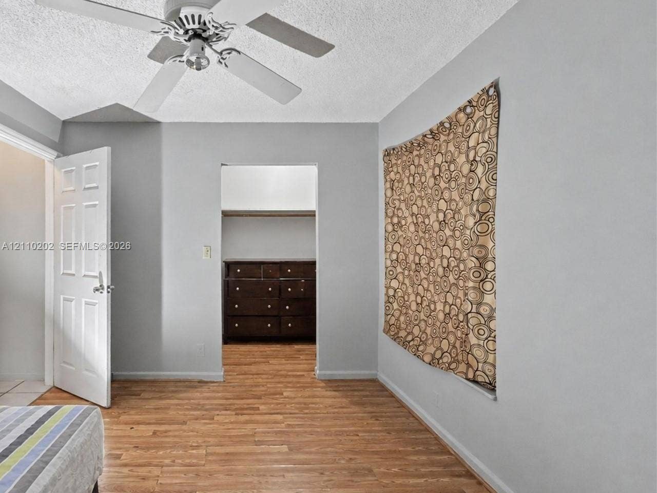 Wood-finish flooring, white paneled door, and ceiling fan with integrated lighting