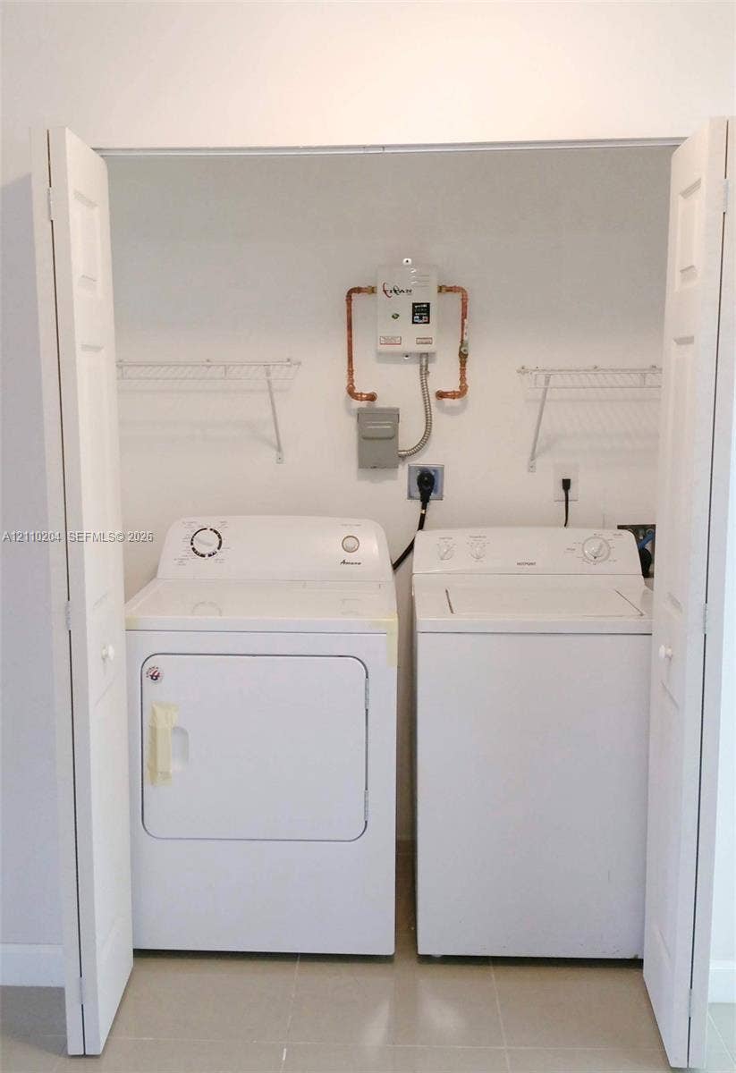 Laundry closet featuring bi-fold doors, wall-mounted wire shelving, and an on-demand tankless water heater