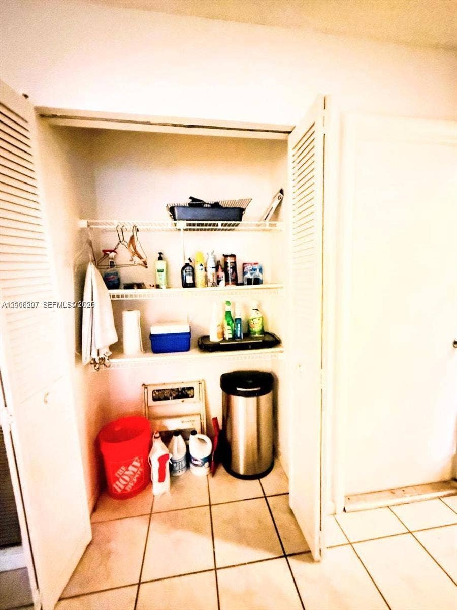 766 NW 24th Avenue, Delray Beach, FL 33445 Storage closet featuring dual louvered doors and three tiers of built-in wire shelving, finished with tile flooring