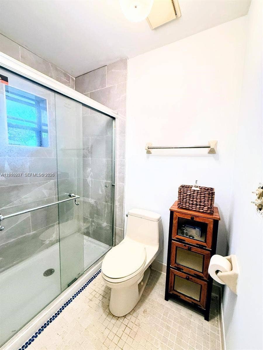 766 NW 24th Avenue, Delray Beach, FL 33445 Walk-in shower with floor-to-ceiling tile surround and sliding glass doors, integrated toilet, and tiled flooring