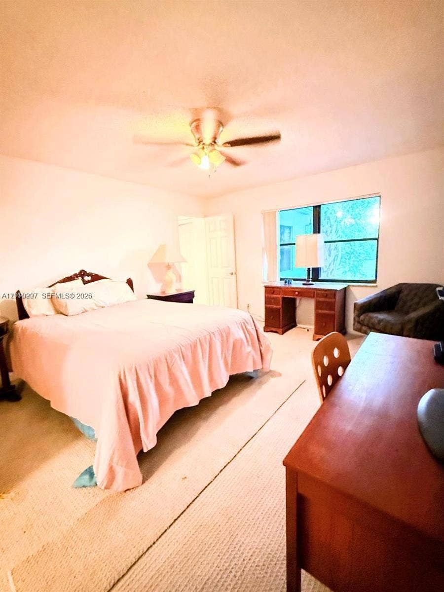 766 NW 24th Avenue, Delray Beach, FL 33445 Neutral-toned carpeting, multi-pane window, and central ceiling fan with integrated lighting