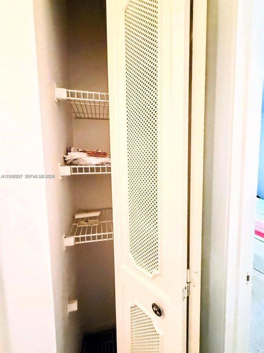 766 NW 24th Avenue, Delray Beach, FL 33445 Storage closet featuring bi-fold doors with louvered panels and tiered wire shelving