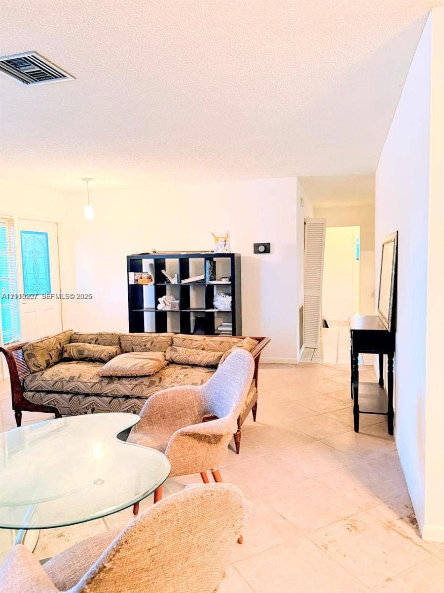 766 NW 24th Avenue, Delray Beach, FL 33445 Open-concept interior featuring light-toned tile flooring, neutral wall finishes, and a decorative glass-panel entry door
