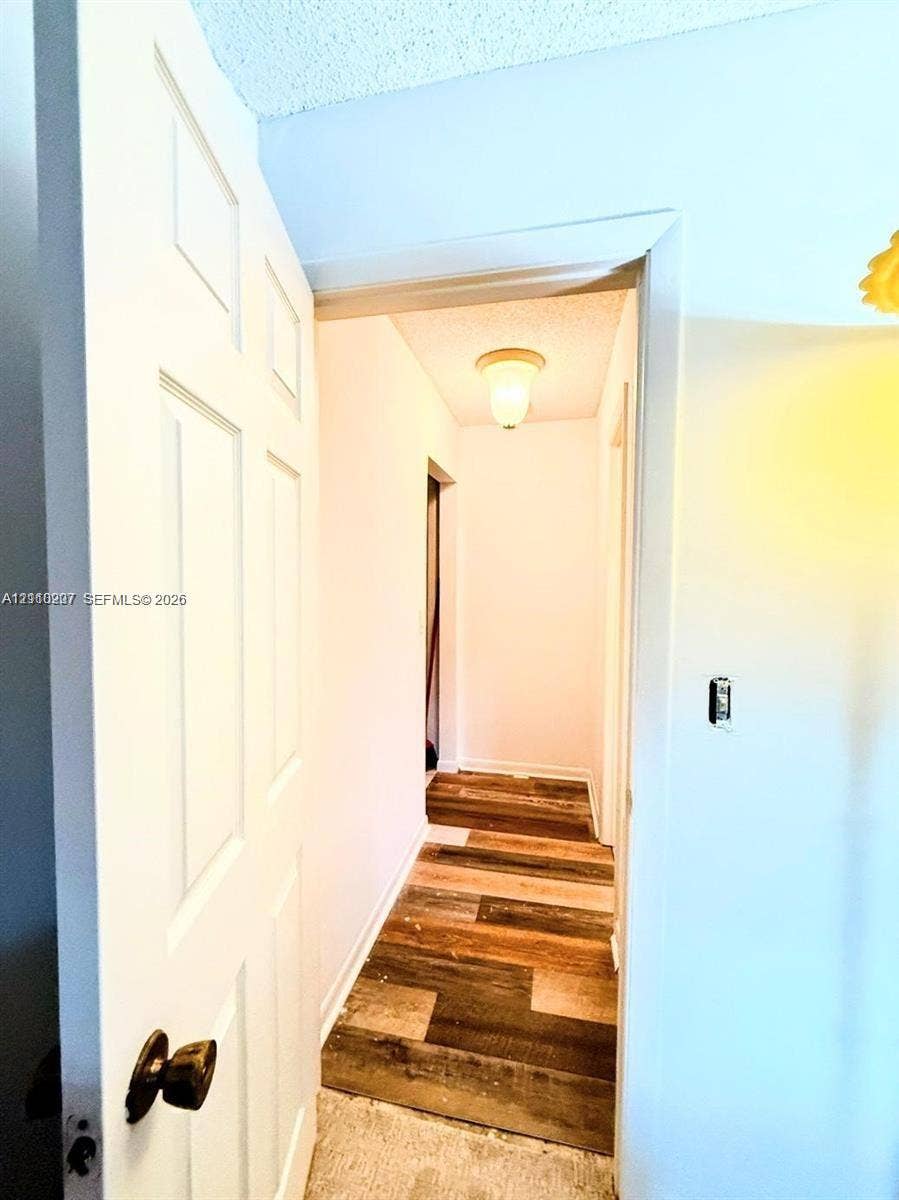 766 NW 24th Avenue, Delray Beach, FL 33445 Six-panel interior door with dark metal hardware, flush-mount ceiling lighting, and wood-finish flooring