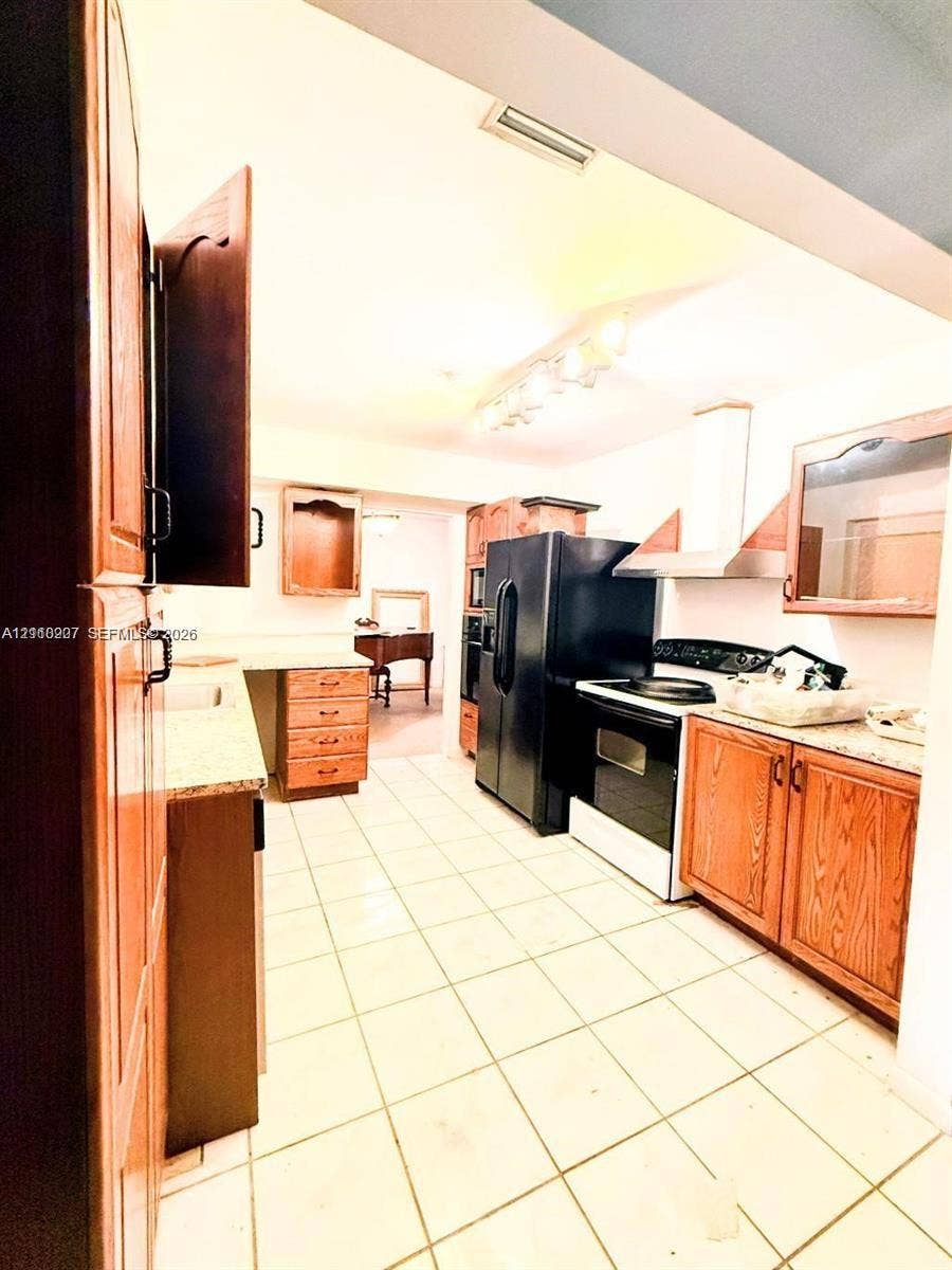 766 NW 24th Avenue, Delray Beach, FL 33445 Kitchen featuring wood cabinetry, stone countertops, ceramic tile flooring, a stainless steel range hood, and track lighting