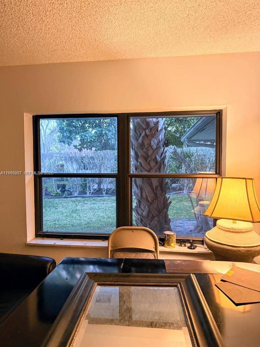 766 NW 24th Avenue, Delray Beach, FL 33445 Double-pane window featuring a dark frame and a ledge overlooking an outdoor area with mature palm trees and greenery