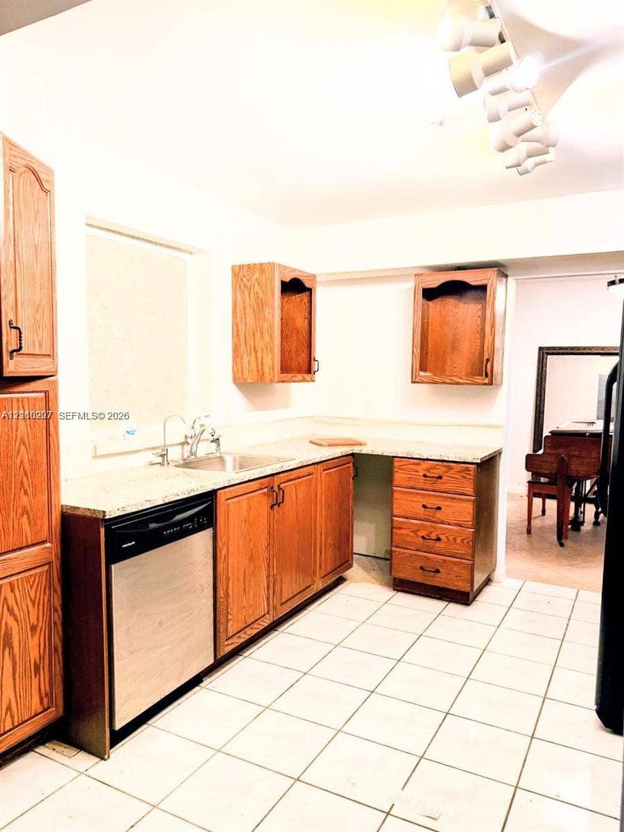 766 NW 24th Avenue, Delray Beach, FL 33445 Kitchen featuring wood cabinetry, stone-finish countertops, stainless steel dishwasher, undermount sink, and ceramic tile flooring