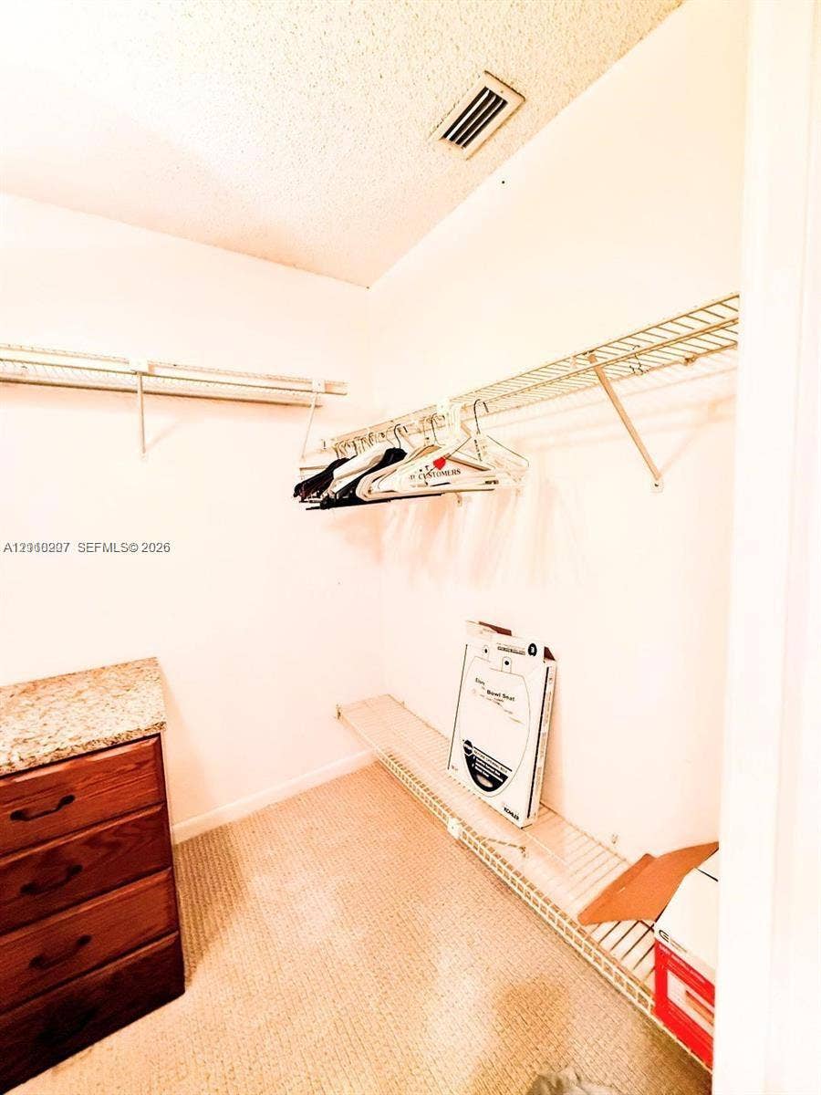 766 NW 24th Avenue, Delray Beach, FL 33445 Storage space featuring wire shelving and a built-in wooden cabinet with a stone-finish countertop