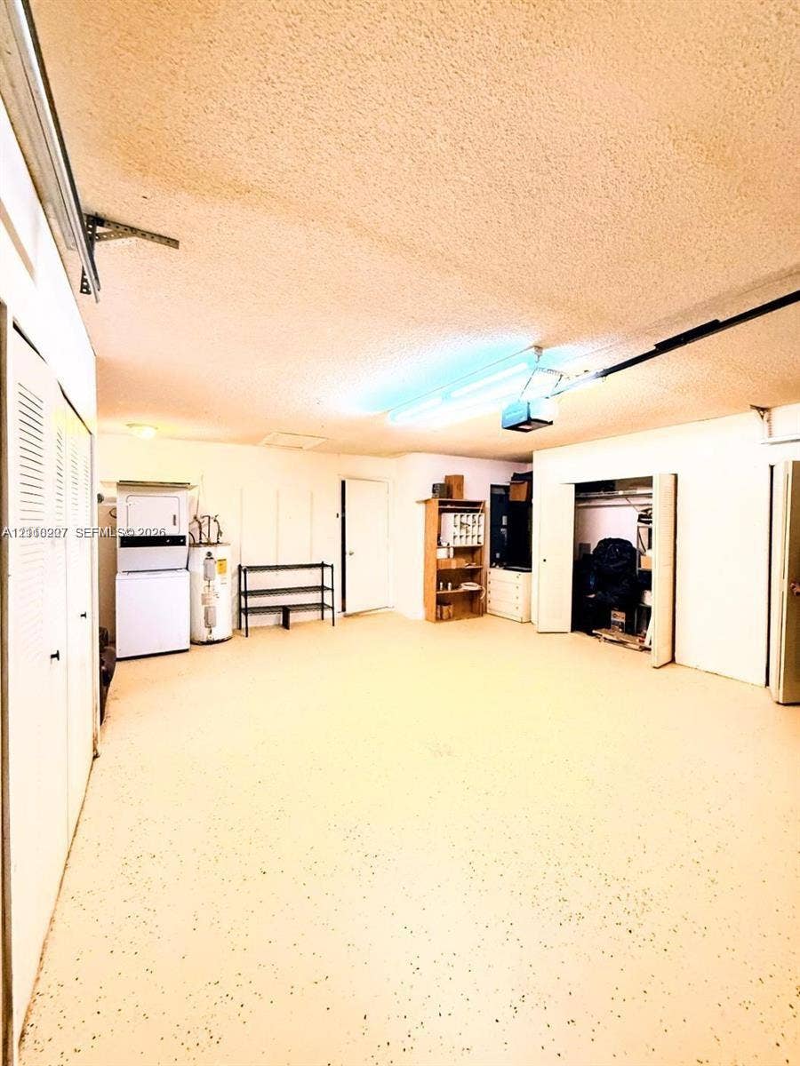 766 NW 24th Avenue, Delray Beach, FL 33445 Garage featuring an epoxy-coated floor, integrated laundry hookups, built-in storage shelving, and overhead fluorescent lighting