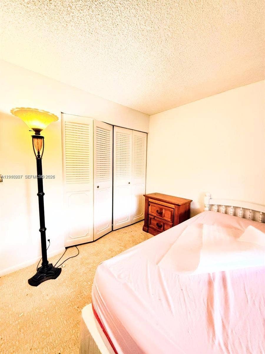 766 NW 24th Avenue, Delray Beach, FL 33445 Room interior featuring floor-to-ceiling white louvered bifold closet doors and wall-to-wall carpeting
