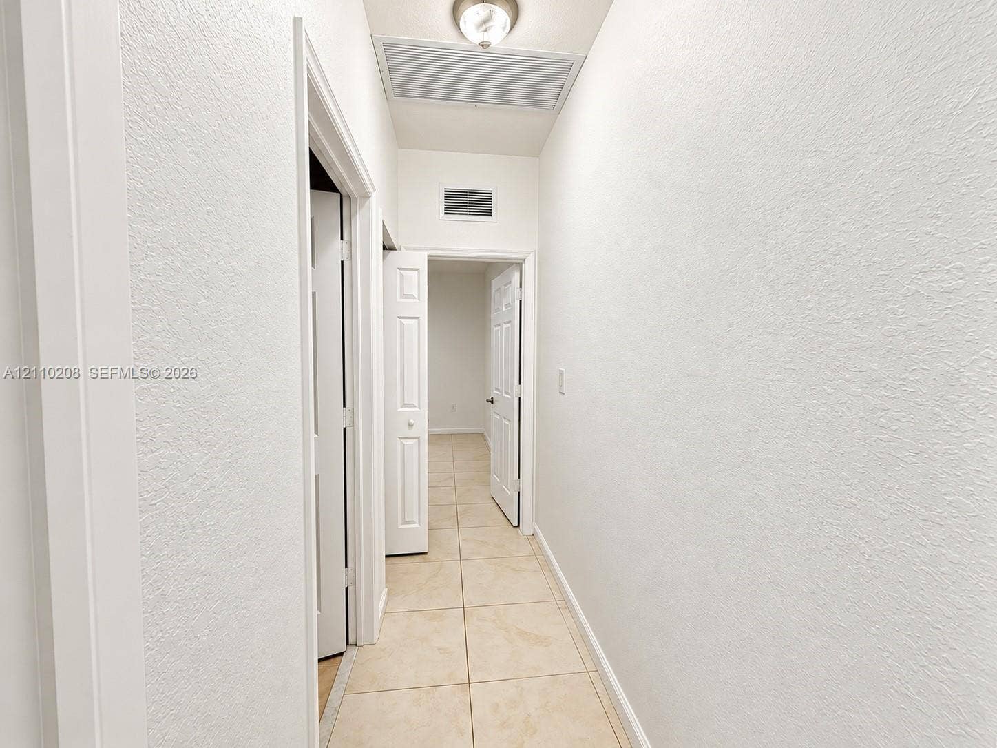 657 SE 30th Terrace, #A, Homestead, Homestead, FL 33033 Interior hallway featuring neutral ceramic tile flooring, textured wall finishes, and multi-panel interior doors