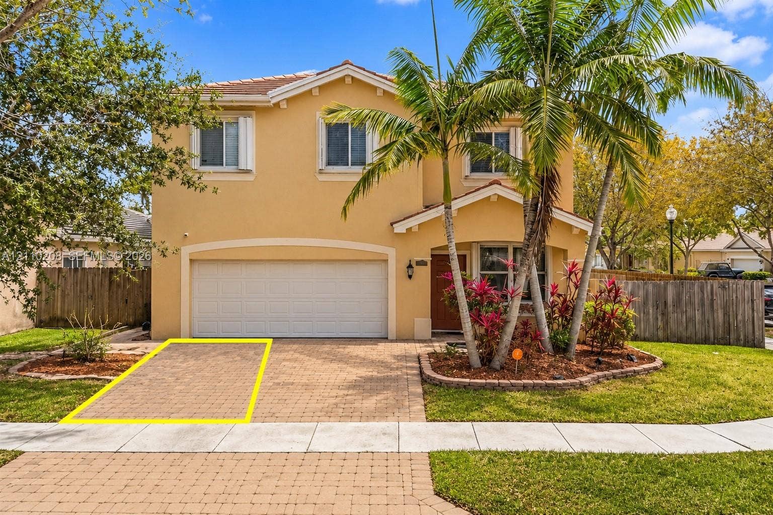 657 SE 30th Terrace, #A, Homestead, Homestead, FL 33033 Two-story stucco exterior featuring a paved stone driveway, an integrated two-car garage, and landscaped garden beds with mature palms